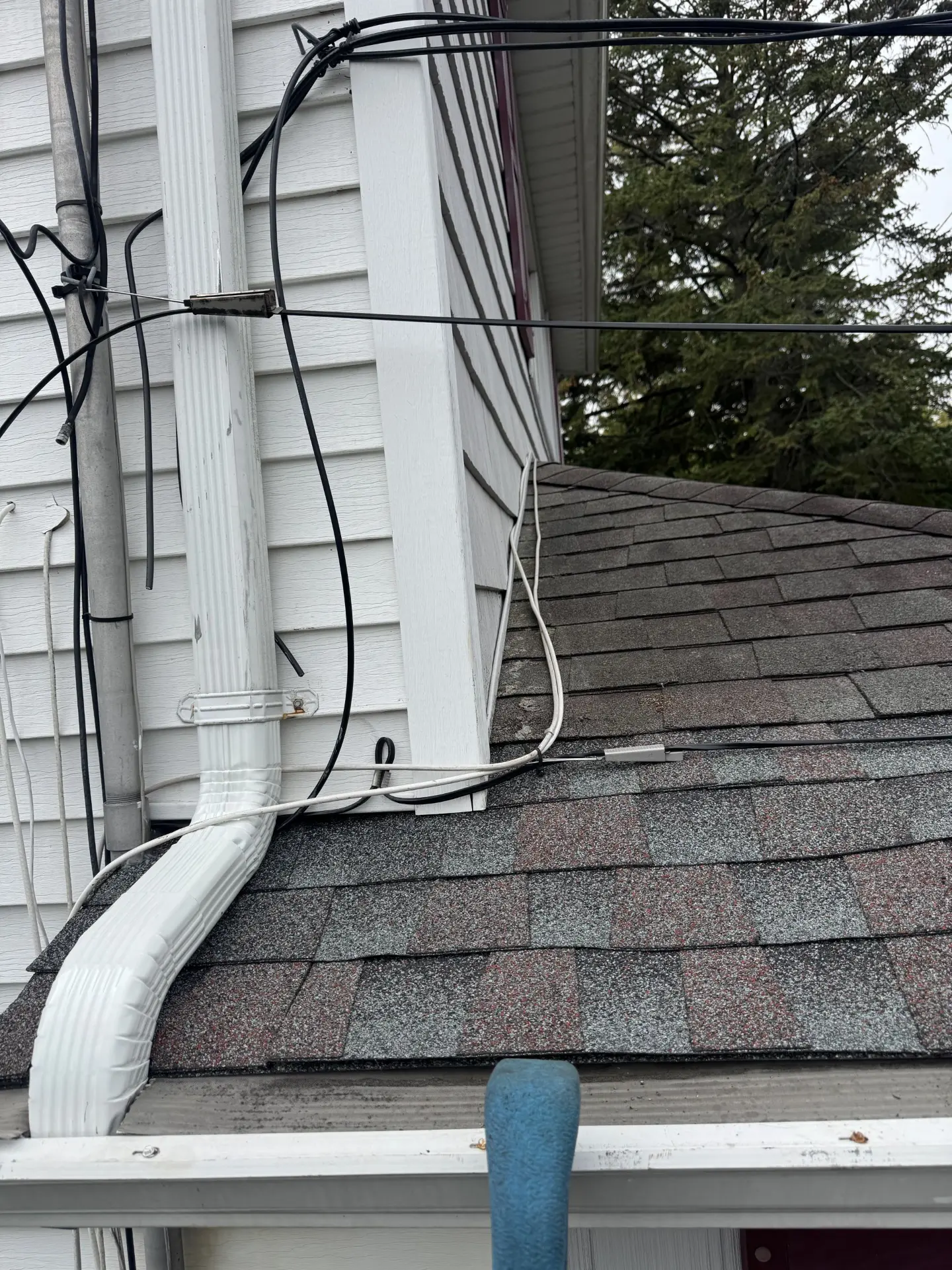 Downspout elbow tied into a lower roof during a gutter repair