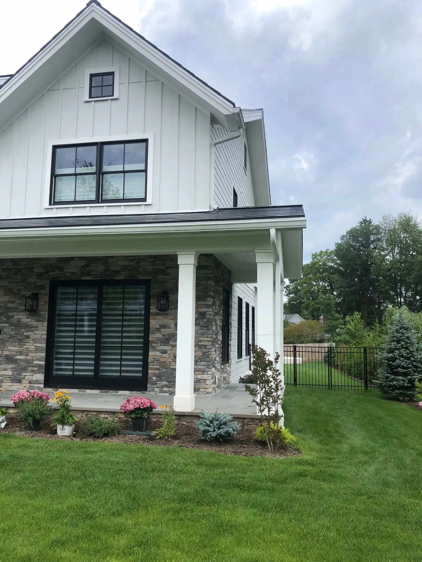 White farmhouse with black seamless gutters over a stone porch