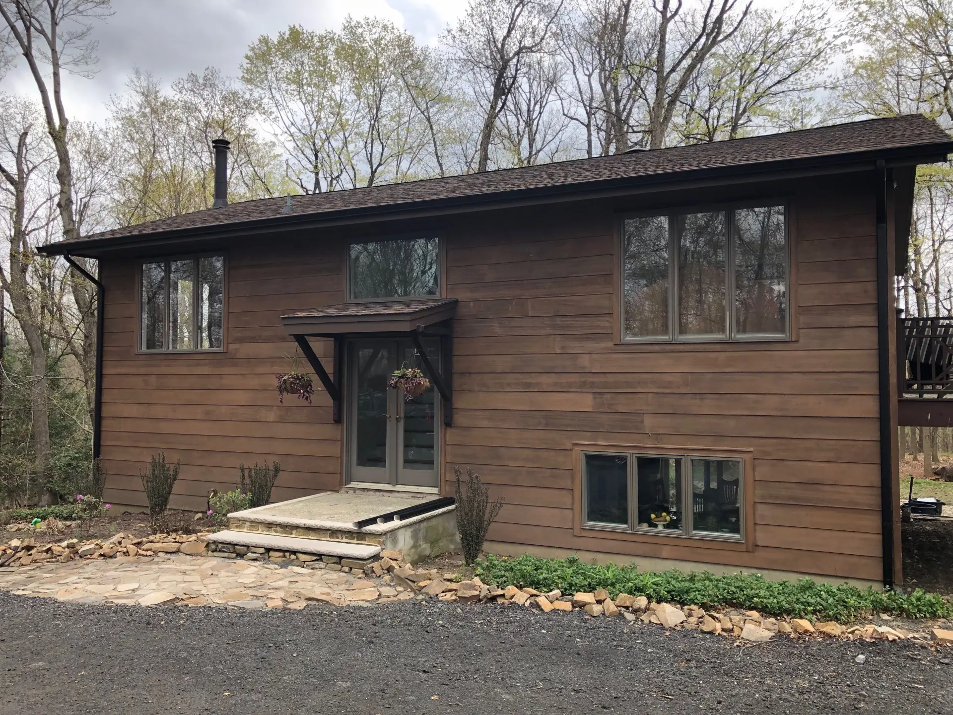 Dark wood-sided home with new dark gutters and downspout along the roofline