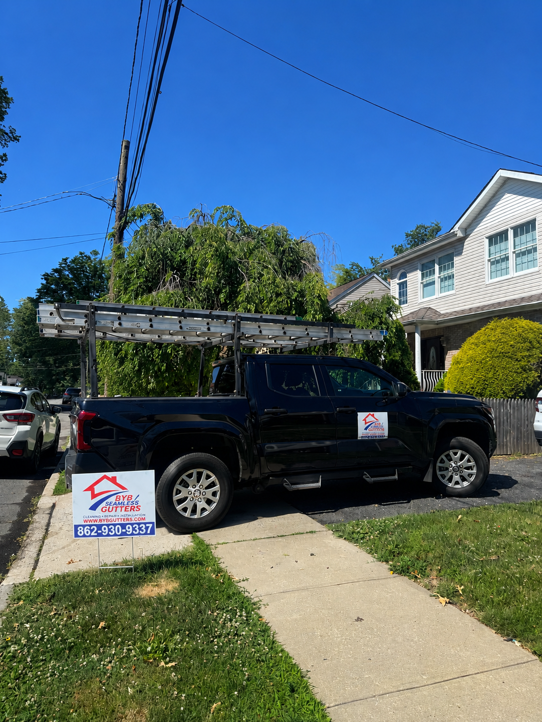 BYB Gutters work truck with ladder racks parked at a job site