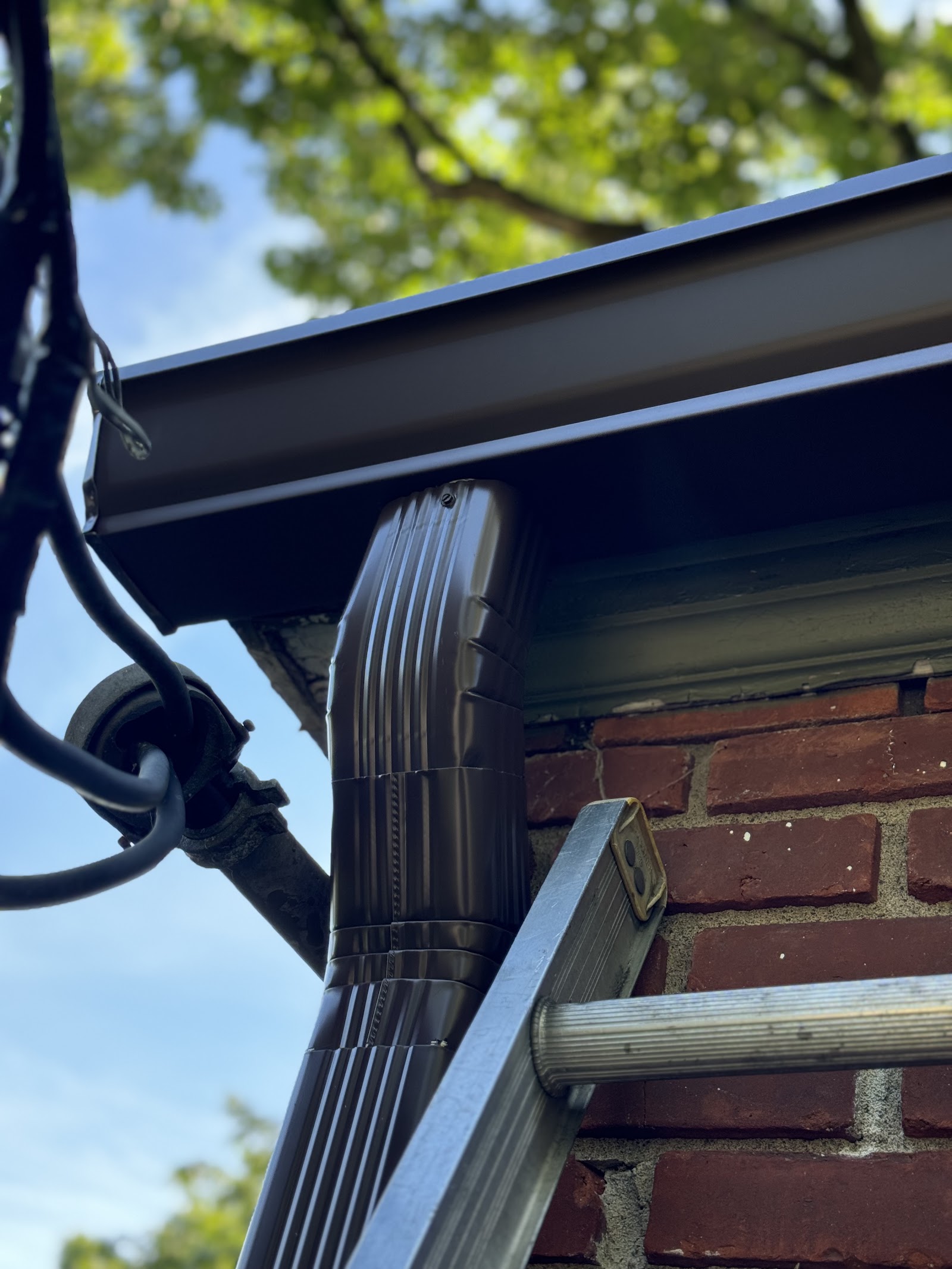 Close-up of a downspout elbow tied into a new gutter run