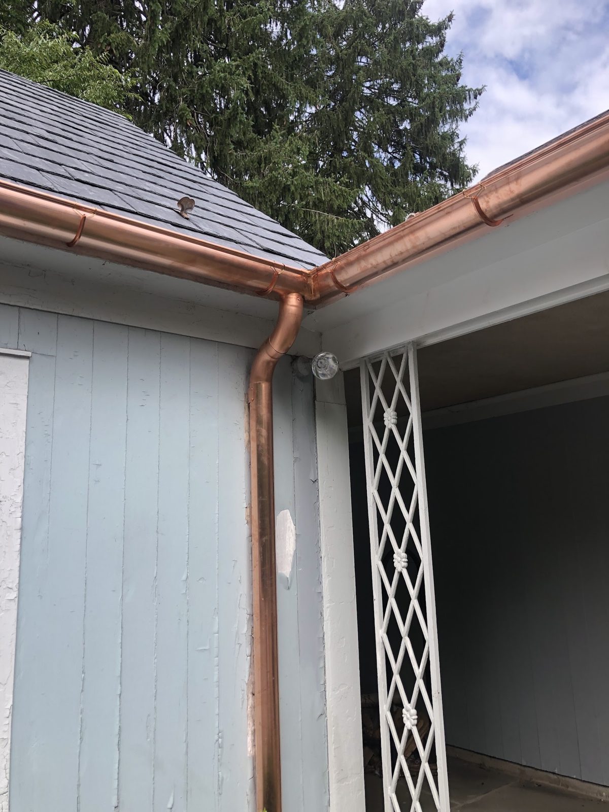Rainwater flowing cleanly through a white residential gutter into the downspout